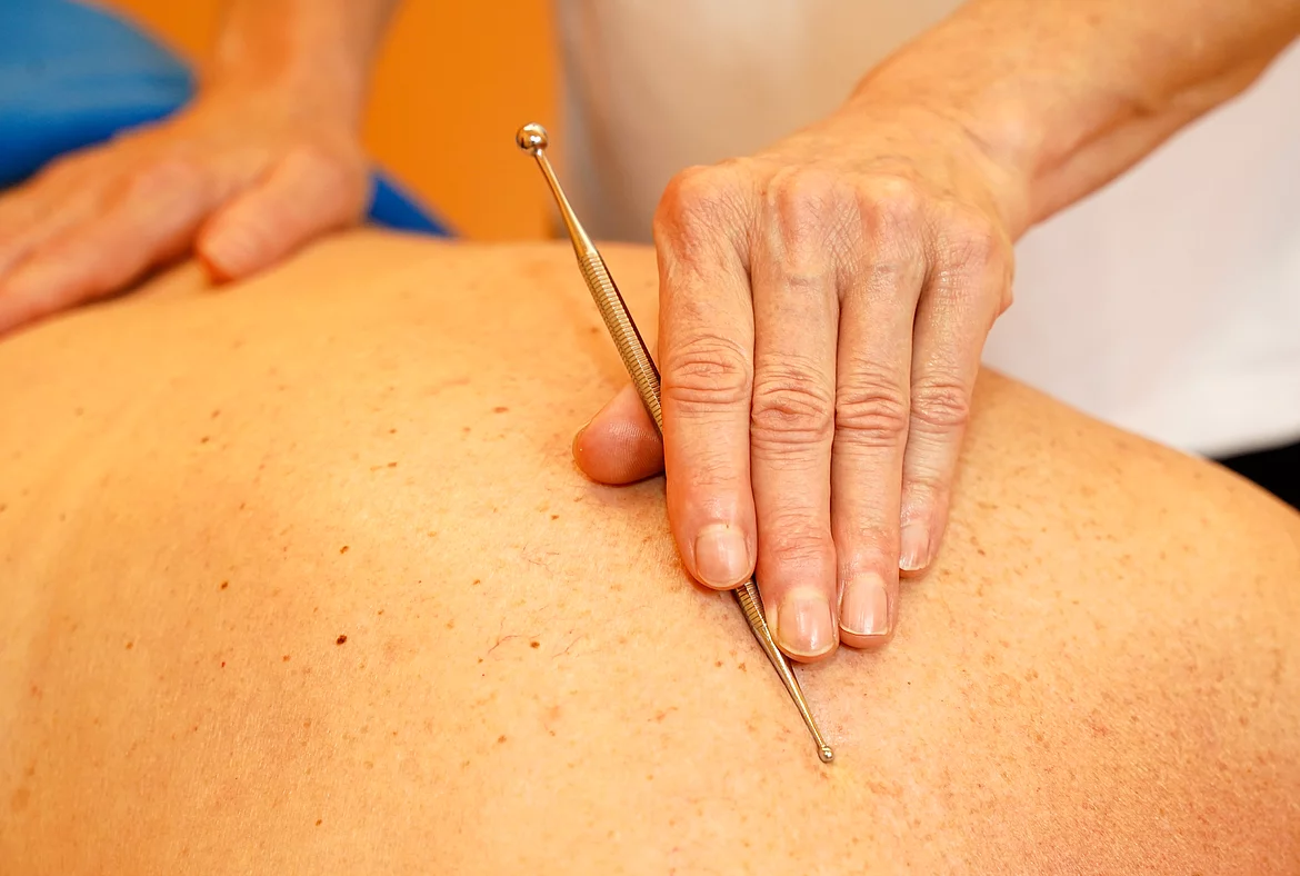 Patientin mit Rheumatoider Arthritis bekommt eine Akupressurbehandlung von Therapeutin im Gasteiner Heilstollen.