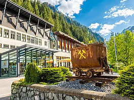 Außenansicht des Gesundheitszentrums Gasteiner Heilstollen mit Bergwerkswagen, der im Bergbau Grubenhunt genannt wird