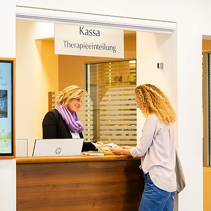 Frau wird von Mitarbeiterin empfangen und bekommt alle Informationen und wird für die Therapie eingeteilt