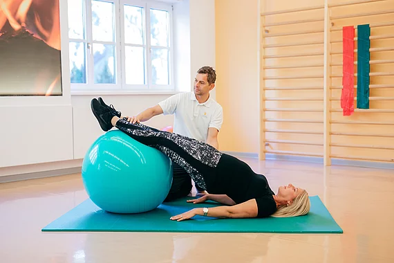 Patientin mit Fibromyalgie bei der Therapie liegt mit Beinen auf dem Gymnastikball im Gasteiner Heilstollen.
