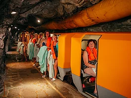 Patientin mit Morbus Bechterew sitzt im Zug im Gasteiner Heilstollen, Patienten steigen aus.