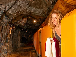 Eine Frau mit Handtuch steigt aus dem Zug bei der Einfahrt im Gasteiner Heilstollen