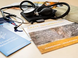 Prospekte, ein Steoskop und ein Blutdruckmessgeraet liegen auf einem Tisch im Gasteiner Heilstollen.