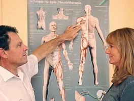 Arzt zeigt beim Erstgespräch mit Patientin mit Rheuma auf die Schautafel im Gasteiner Heilstollen.