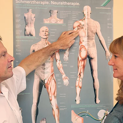 Arzt zeigt beim Erstgespräch mit Patientin mit Rheuma auf die Schautafel im Gasteiner Heilstollen.