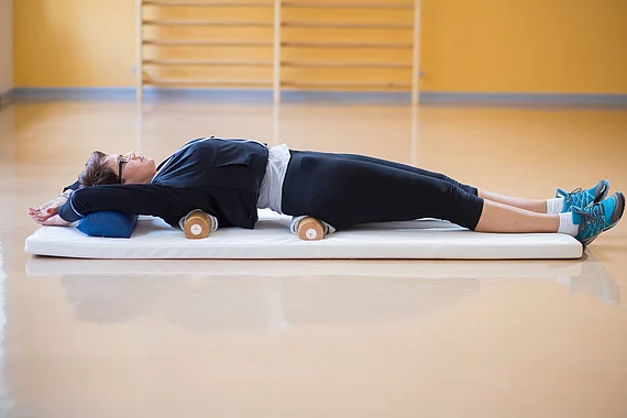 Gasteiner Heilstollen Patientin mit Fibromyalgie bei einer Physiotherapie mit Ball mit Lagerungsrollen.