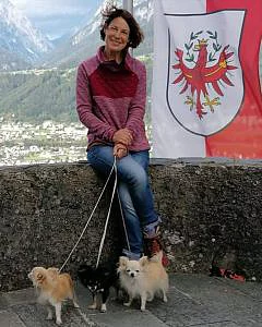 Frau mit Hunden vor Fahne erzählt von Erfahrungen im Gasteiner Heilstollen.