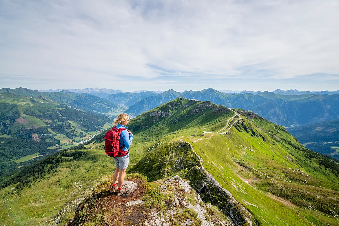 Wandern Stubner (c) Gasteinertal Tourismus GmbH, Christoph Obers Wanderin steht am Stubnerkogel und blickt über die Gasteiner Berge