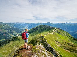 Wandern Stubner (c) Gasteinertal Tourismus GmbH, Christoph Obers Wanderin steht am Stubnerkogel und blickt über die Gasteiner Berge