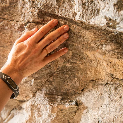 Hand einer Patientin berührt das Gestein des Gasteine Heilstollen während der Radontherapie