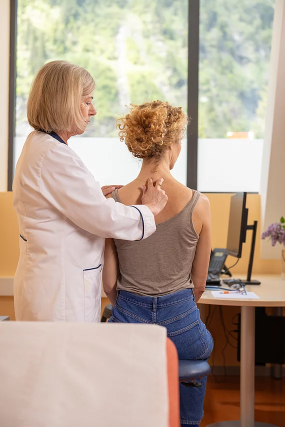 Ärztin untersucht den Rücken/Wirbelsäule der Patientin