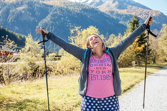 Patientin mit Fibromyalgie vom Gasteiner Heilstollen freut sich und streckt Hände in die Höhe.