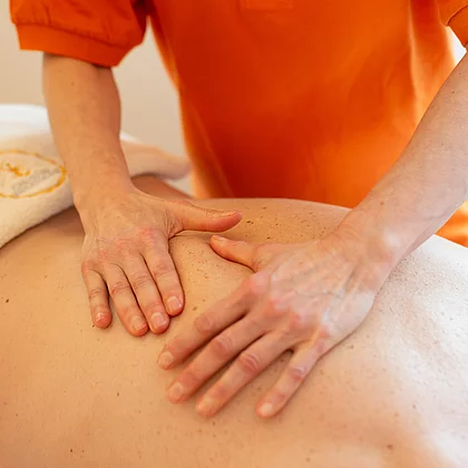 Die Masseurin massiert den Mann am Rücken